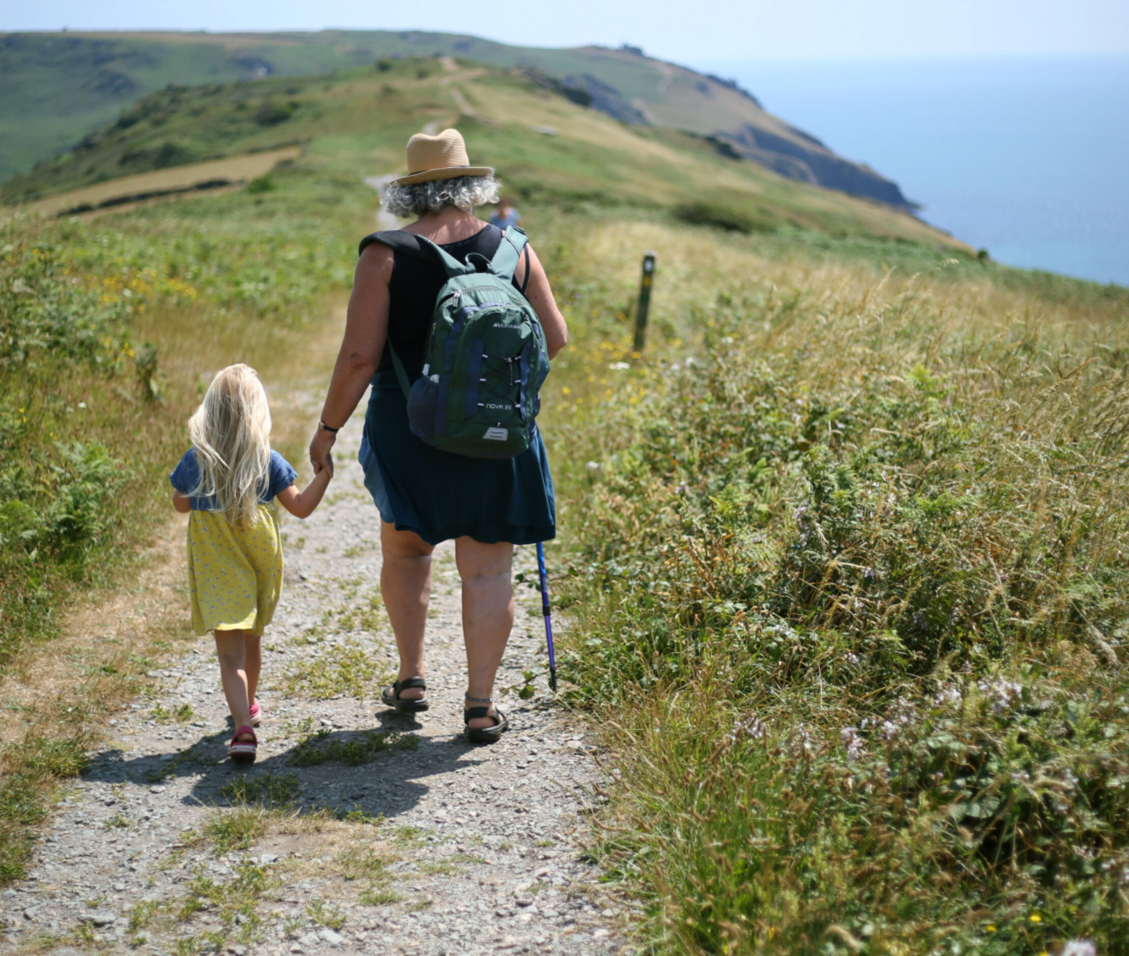Child and grandmother walking together on a coastal path